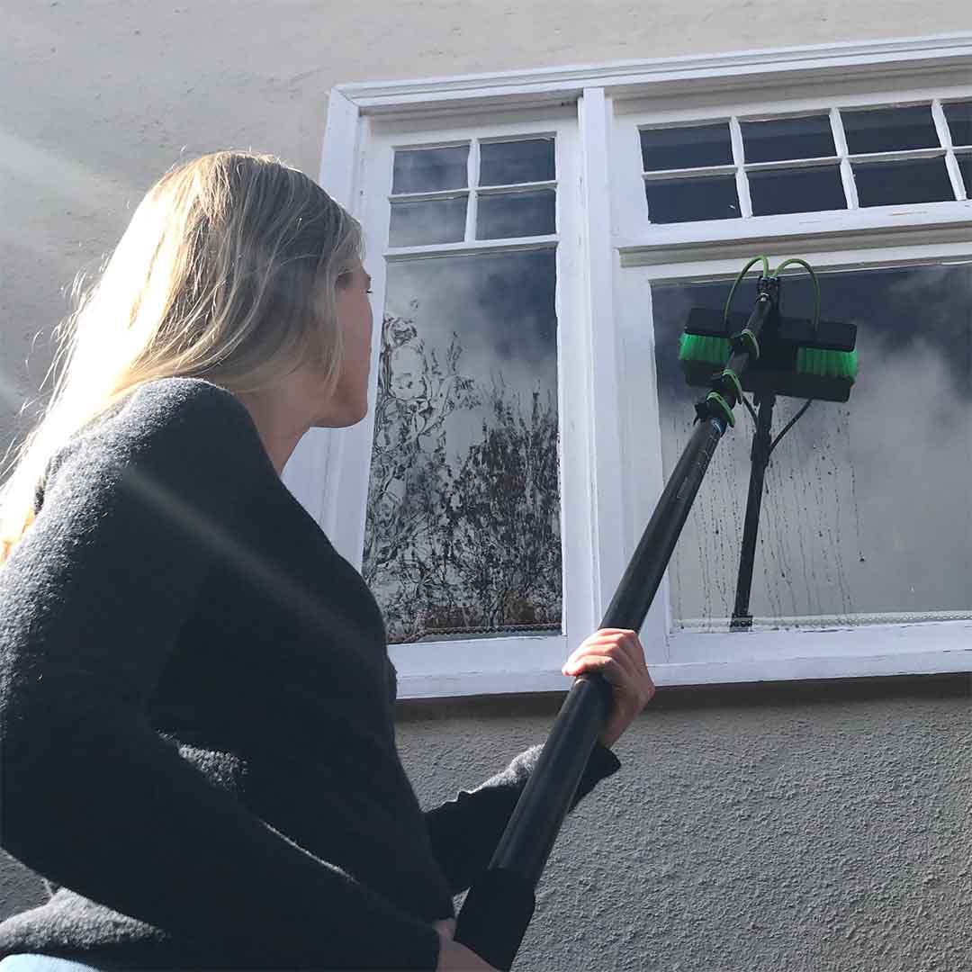 A woman using the Aluminum Water Fed pole for window cleaning.