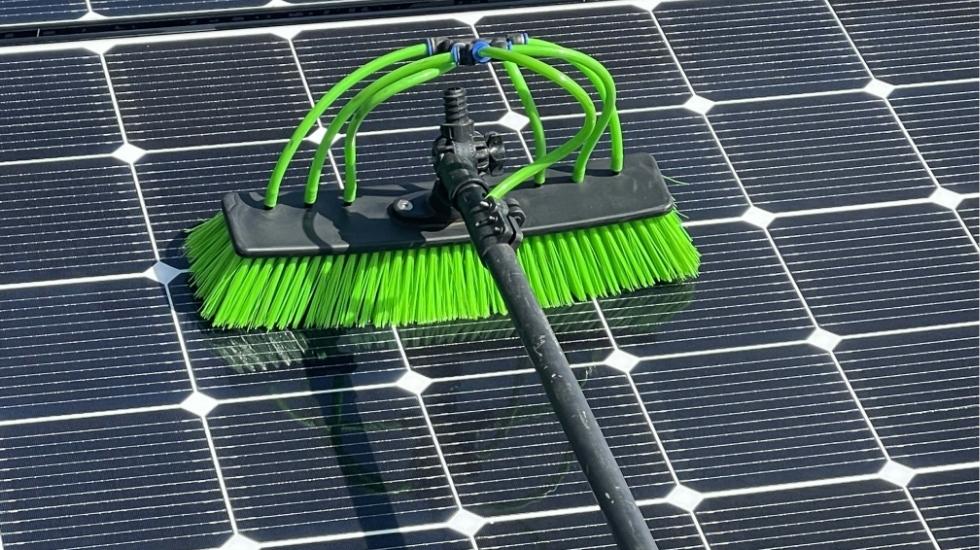 Close-up of a green brush attached to a water-fed pole cleaning solar panels