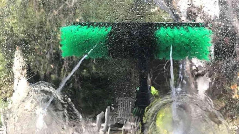A water fed pole brush spraying water, designed for efficient cleaning of solar panels or windows.