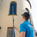 Equipmaxx professional using extended Venom water fed pole to clean high arched stucco windows.