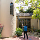 Fully extending the Venom water fed pole system to clean high, second-story arched windows on a stucco turret building.