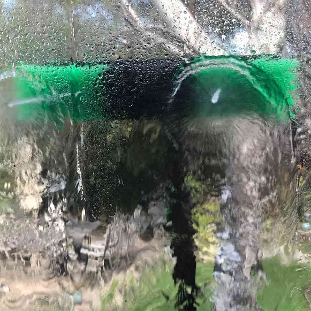 Water fed pole brush head nozzle spraying water to clean window.